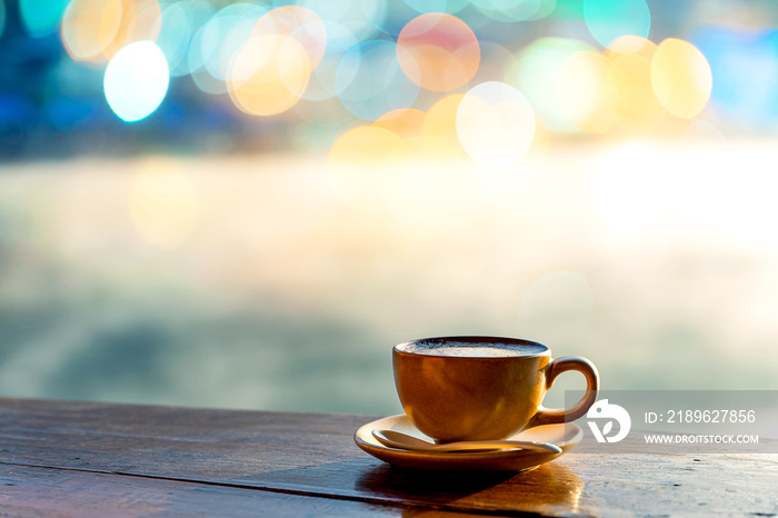 木桌上的热咖啡杯，温暖的阳光和清晨湖面上的薄雾，映衬着模糊的C