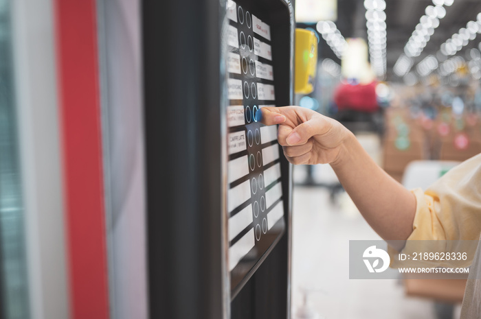 Asian woman buying can drink from vending machine in airport