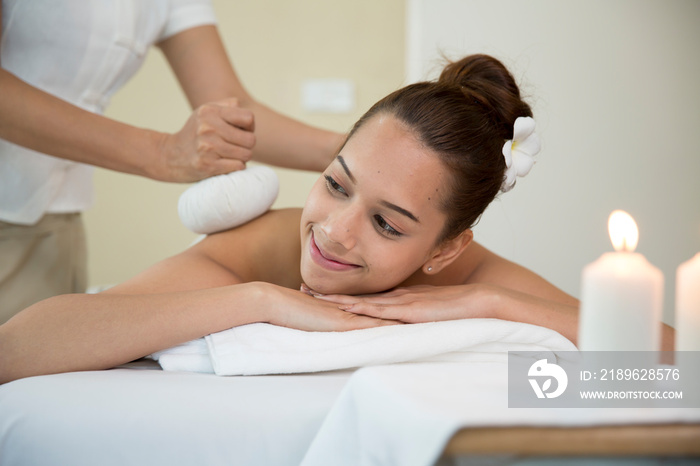 Asian woman laying on bed for herb compress and pampering thai massage therapist, relaxation and wel