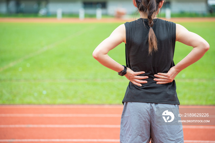 Back view of young runner woman suffering from Backache or Sore waist after running in the running t