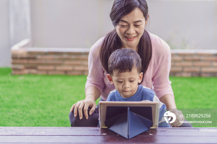 Asian family with son are looking the cartoon via technology tablet and playing together when living