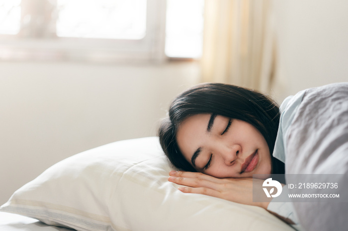 Young adult asian woman sleep in bedroom on morning. Stay at home tired from study and work resting 