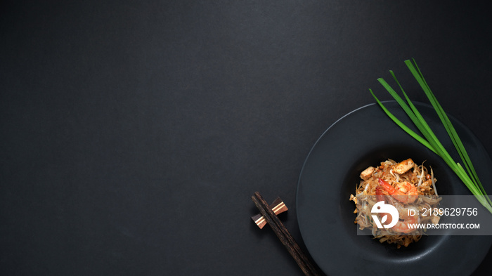 Pad Thai的俯视图，在黑ta上的黑色陶瓷盘中搅拌虾和鸡蛋的泰国面条