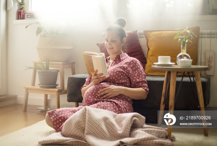 Pregnant woman relaxing  at home and reading book.