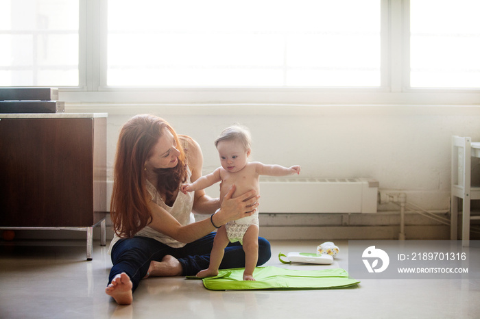 Mother changing baby girls (6-11 months) diaper