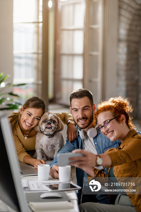 Team of happy business coworkers taking selfie with their dog in the office.