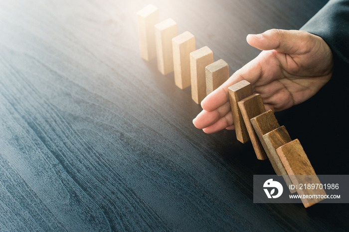 Close up of businessgirl hand Stopping Falling wooden Dominoes effect from continuous toppled or ris