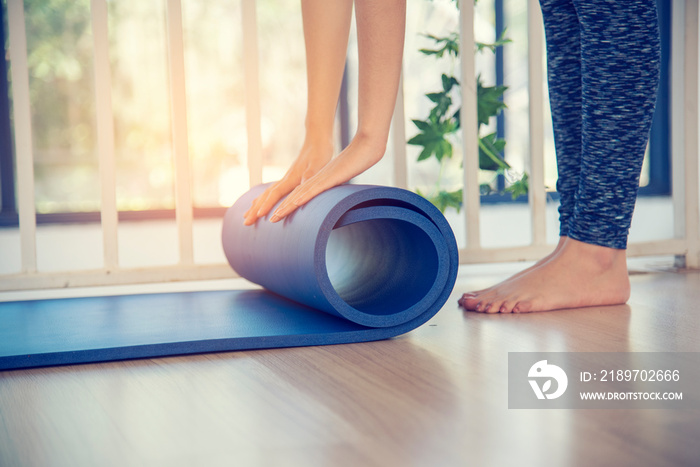 Woman hands rolled up yoga mat on gym floor in yoga fitness training room. Home workout woman close 