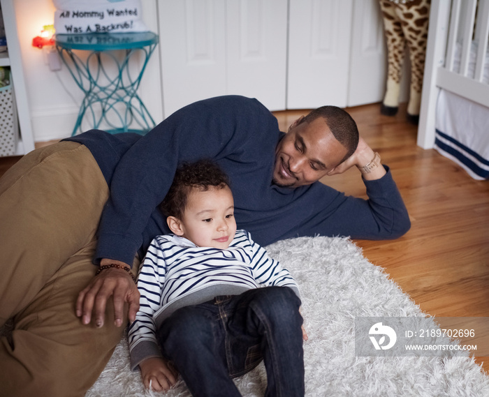 High angle view of father with cute son relaxing on rug at home