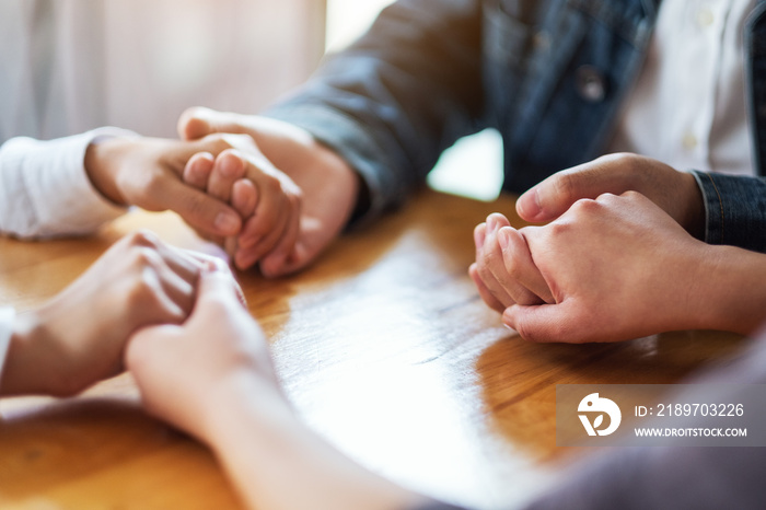 Group of people sitting in a circle holding hands and pray together or in therapy session