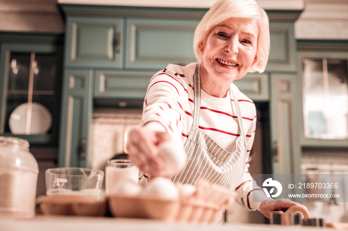 Positive delighted granny cooking biscuits for granddaughter