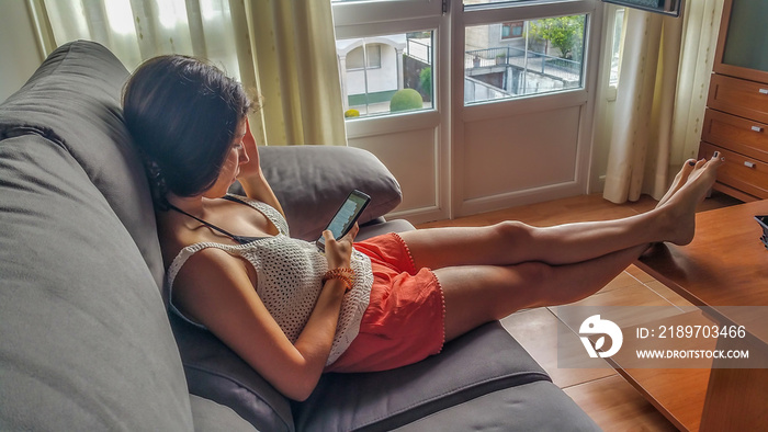 girl sitting on a couch watching her cell phone.