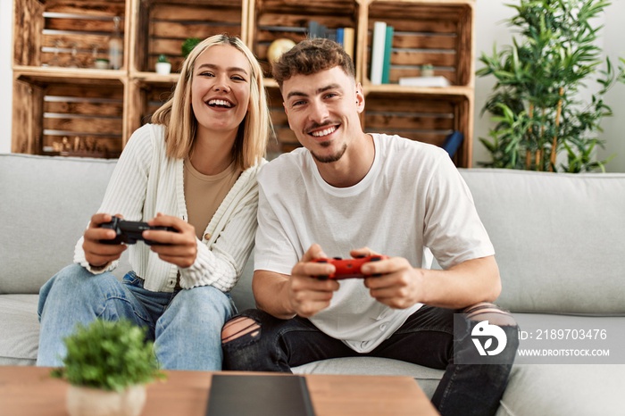 Young caucasian couple smiling happy playing video game at home.