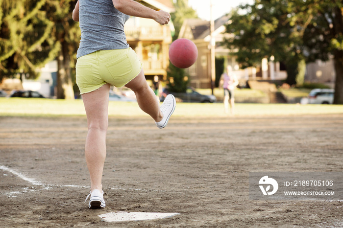 Woman hitting ball in dirt field