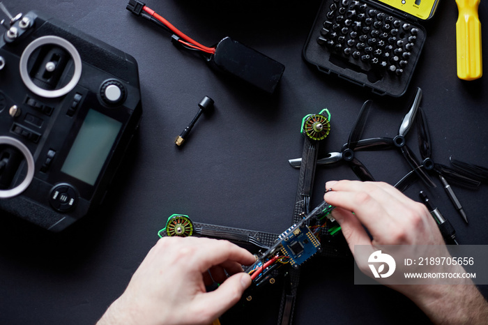 Close up of mans hands assembling a FPV drone from parts, using tools, Preparing high-speed racing 