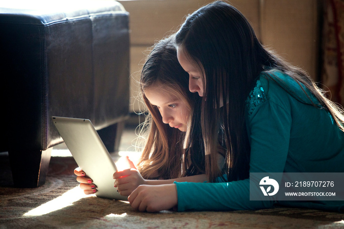 Siblings using digital tablet at home