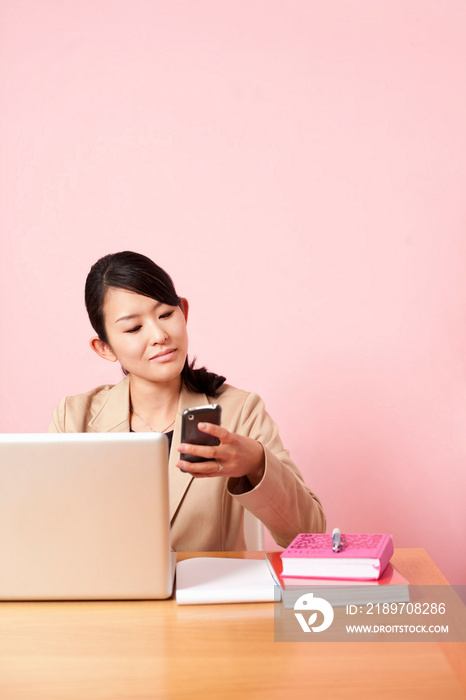 Mid adult woman looking at mobile phone at desk