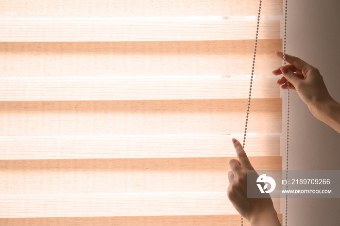 Woman opening blinds on window