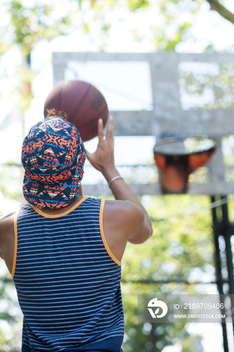 Rear view of young man holding a basketball, ready to shoot