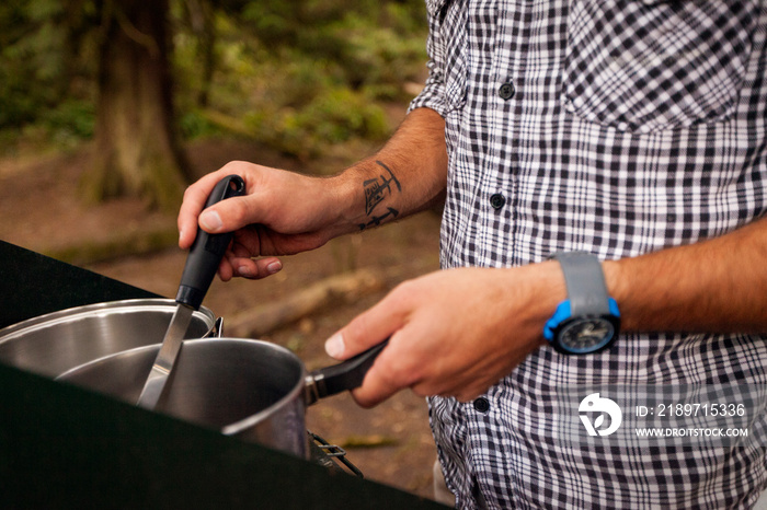 Young man cooking on camping trip