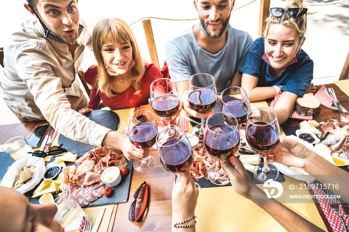 Friends toasting red wine at restaurant bar with open face masks - New normal lifestyle concept with