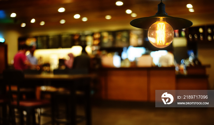 悬挂的复古灯装饰在焦点不集中的餐厅内部背景中发光。