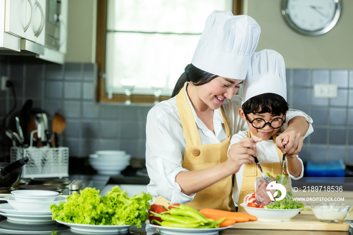 健康家庭。母亲和孩子在厨房里烹饪和切沙拉新鲜蔬菜。