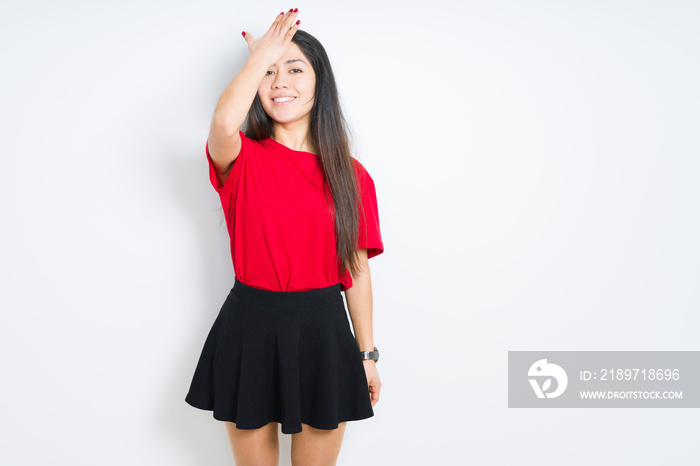 Beautiful brunette woman wearing red t-shirt and skirt over isolated background surprised with hand 