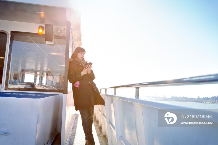 Woman leaning against train cart using smart phone