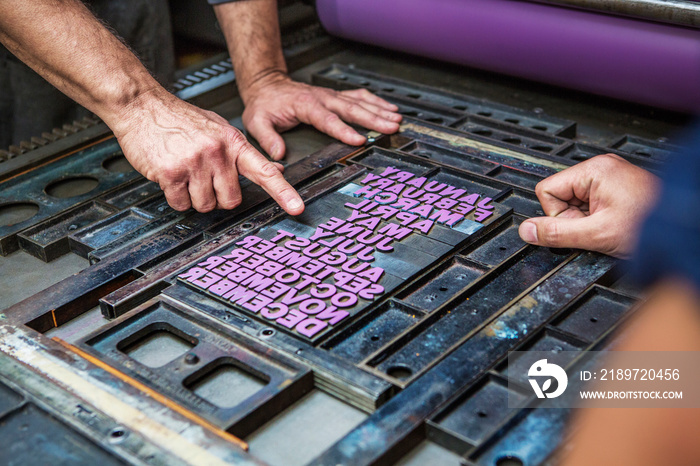 Hands of workers arranging type