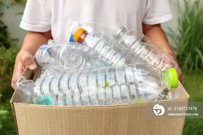 Hand holding brown recycle garbage box with plastic bottles