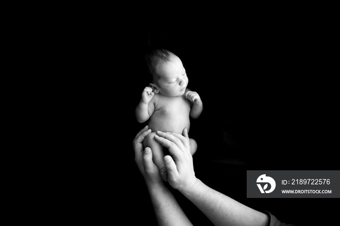 Mom holds her newborn son in her arms. Picture taken on a dark background.