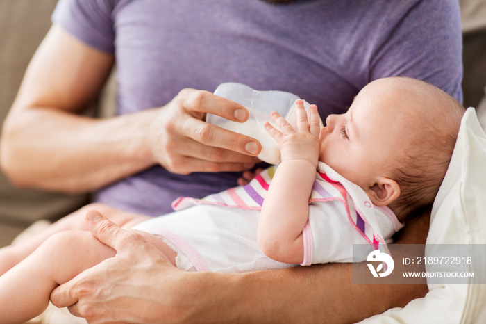 家庭、为人父母和人的概念——父亲用婴儿配方奶粉喂养小女儿的特写