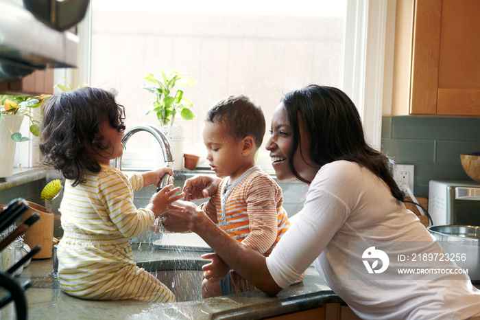 Mother and children (18-23 months) splashing water