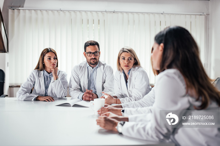 Serious medical team talking while sitting at the table.