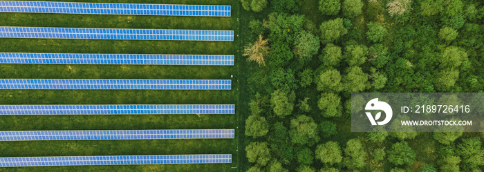 太阳能发电场中的太阳能电池板（太阳能电池）俯视图，绿树成荫，阳光反射。照片
