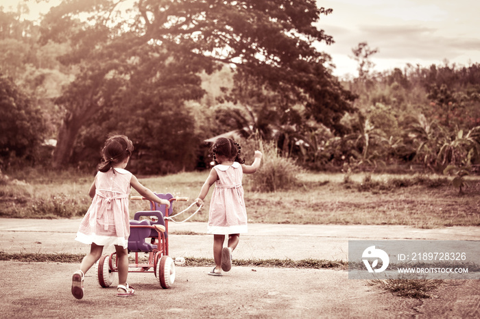 孩子两个小女孩玩得很开心，拉着她的三轮车