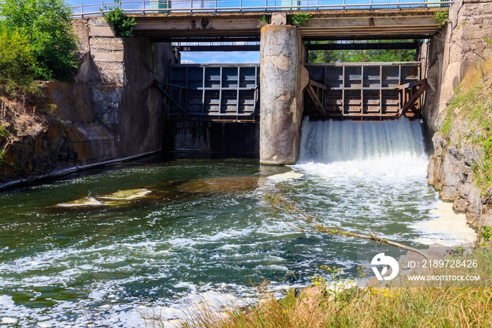 Flowing water with water spray from the open sluice gates of a small dam