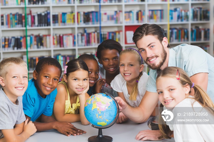 Pupils and teacher looking at globe in library