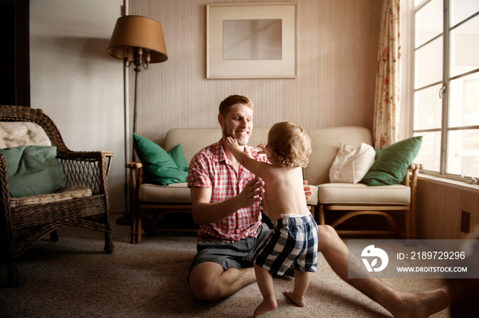 Smiling father playing with his son at home