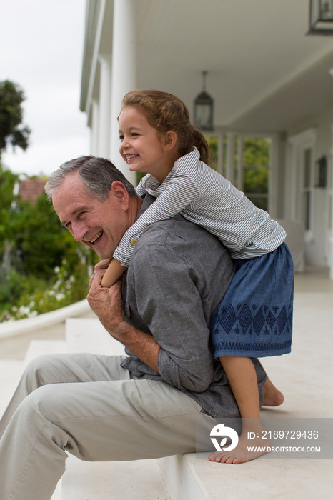 Happy grandfather and granddaughter on patio