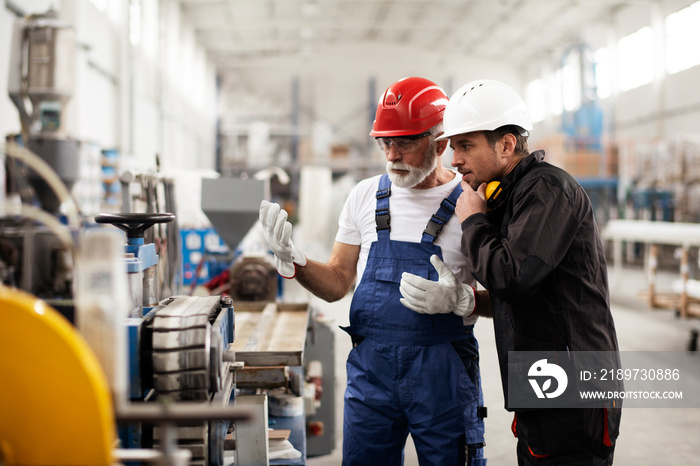 Portrait of workers in factory. Colleagues with helmet working in factory