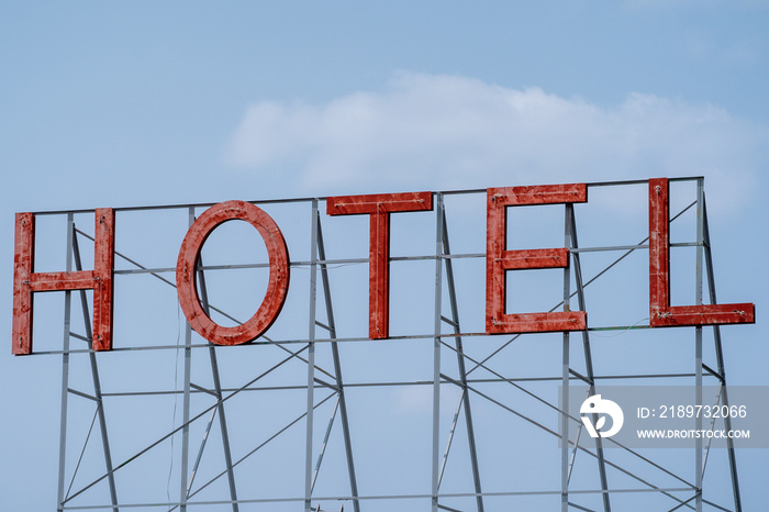 Generic red neon sign for a hotel, against a blue sky