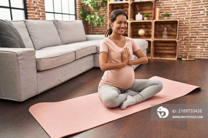 Young latin woman pregnant smiling confident training yoga at home