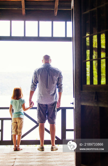 Father and daughter holding hands on balcony