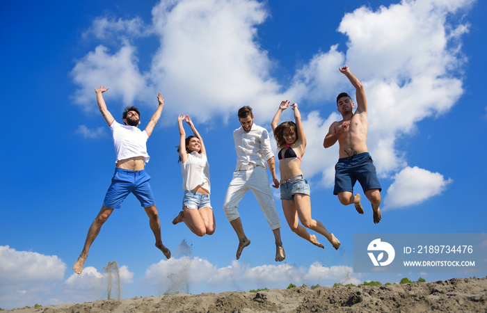 Image of five energetic people jumping at the beach