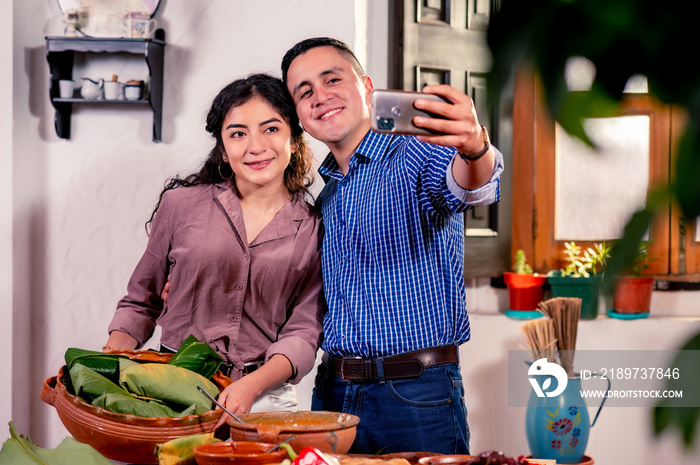 Feliz pareja hispana在电视上自拍。Cocinando tamales。