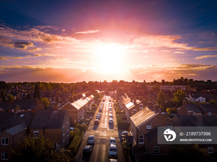 Sun setting with atmospheric effect over traditional British houses and tree lined streets. Dramatic