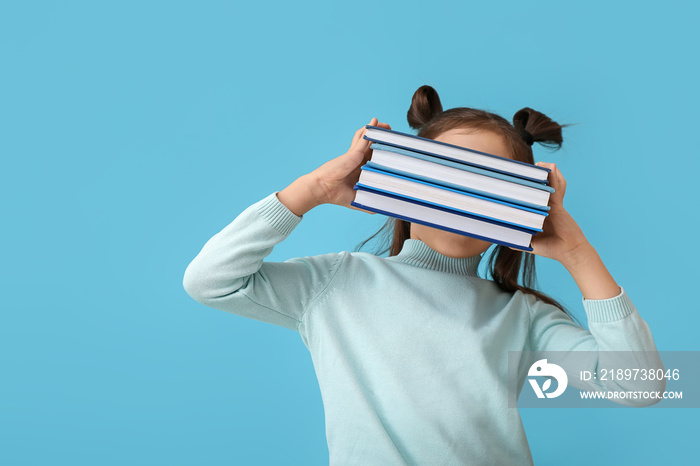 Cute little girl with books on color background