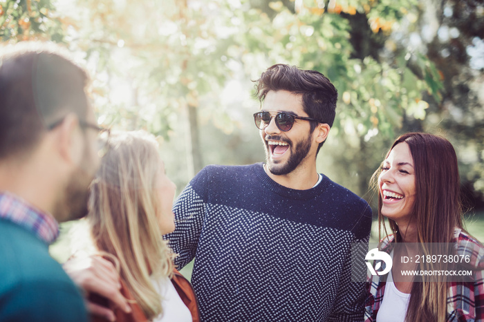 Image of four happy smiling young friends walking outdoors in the park. Love, happiness and friendsh